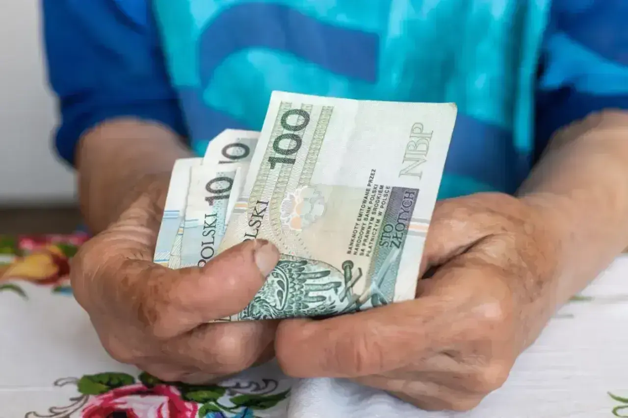 Dłonie trzymają polskie banknoty. Zastanawiasz się, ile wynosi umowa zlecenie na godzinę netto?