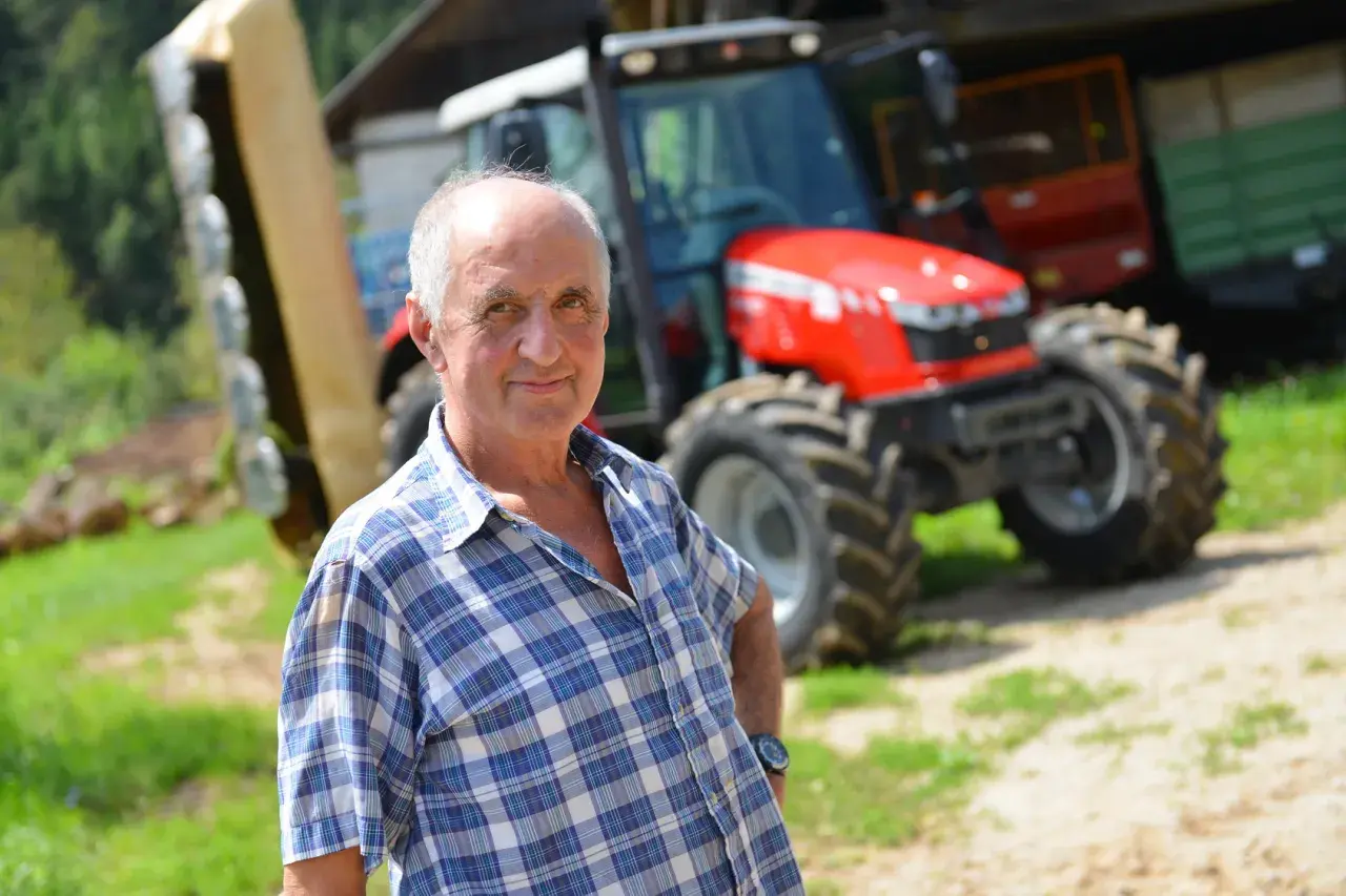 Rolnik w kratę, z dumą prezentuje swój nowy traktor. To dla niego ważny dzień, bo właśnie otrzymał fakturę RR za zakup.