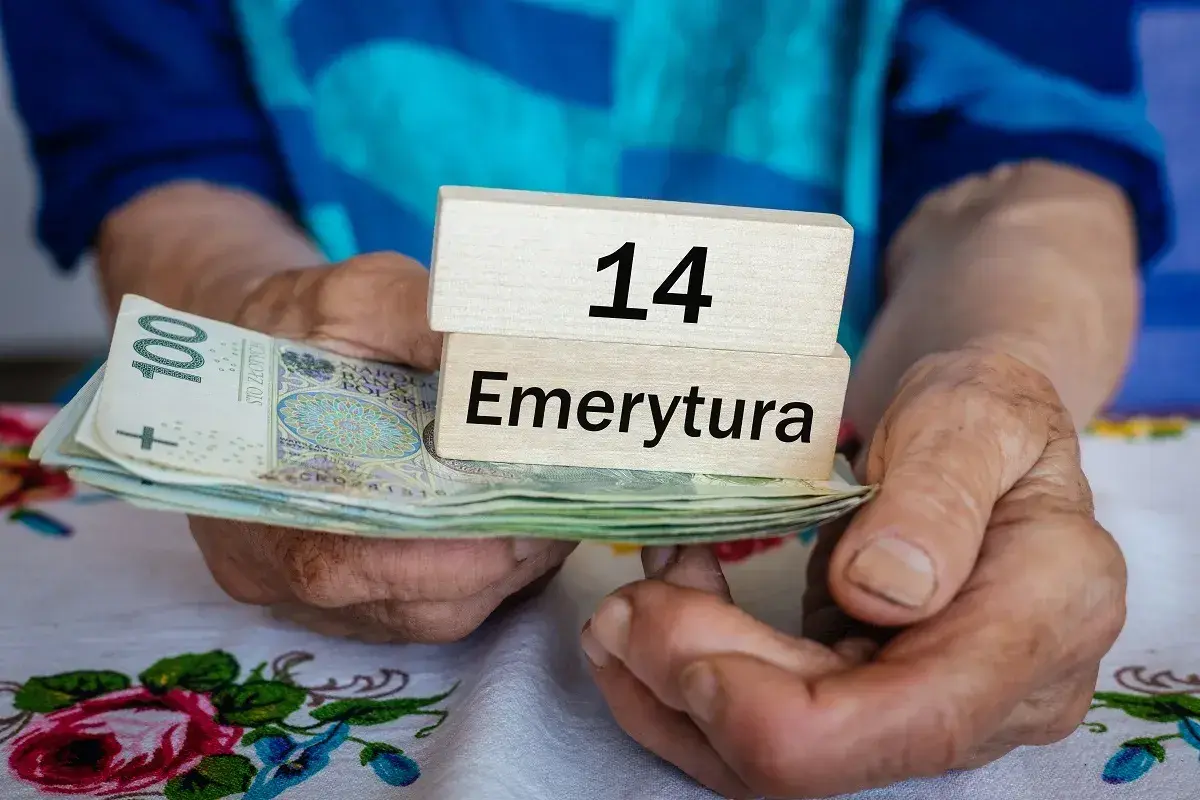 Dłonie trzymają stos banknotów i drewniane klocki z napisami "14" i "Emerytura". Kiedy będą wypłacane czternastki?