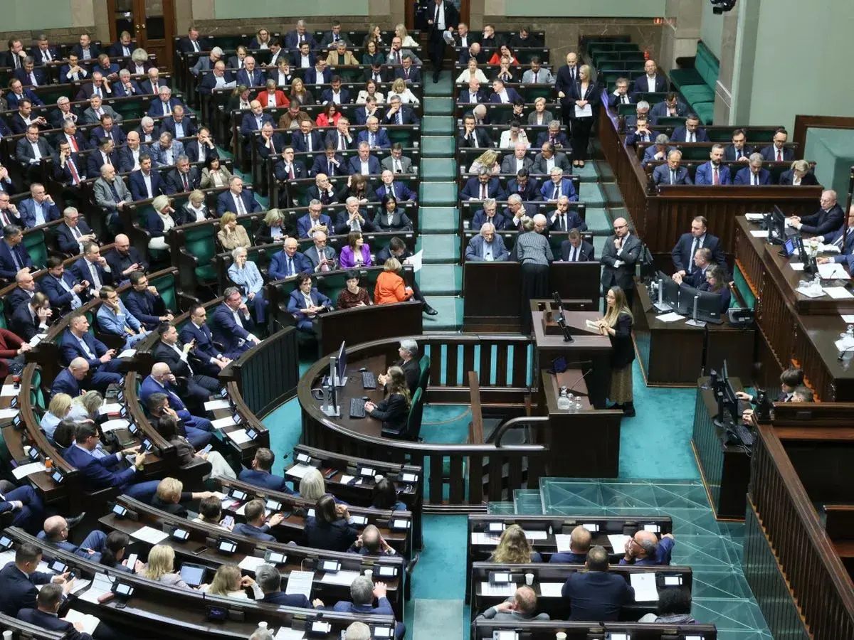 Posłowie w sali sejmowej, dyskutują o tym, ile wynosi dieta poselska.
