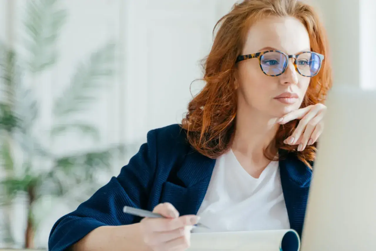Kobieta w okularach z modną oprawką, pracująca przy laptopie. Dofinansowanie do okularów może pomóc w zakupie takich stylowych oprawek.