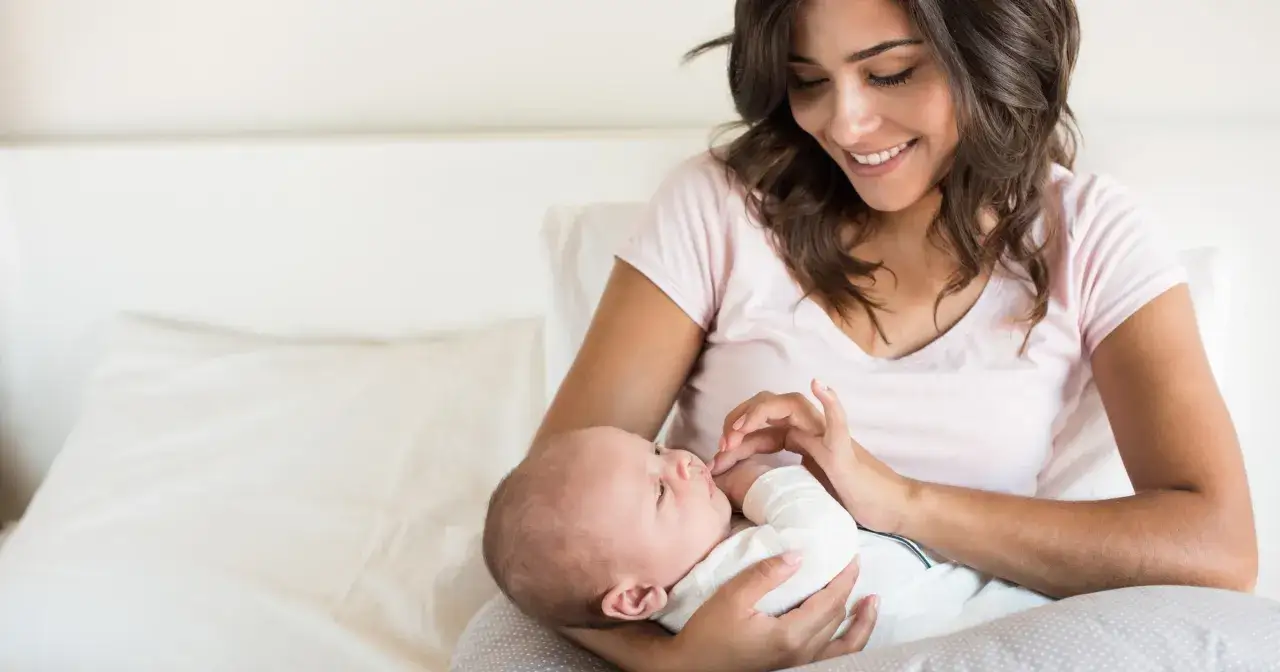 Szczęśliwa mama tuli noworodka, ciesząc się urlopem okolicznościowym z okazji narodzin dziecka.