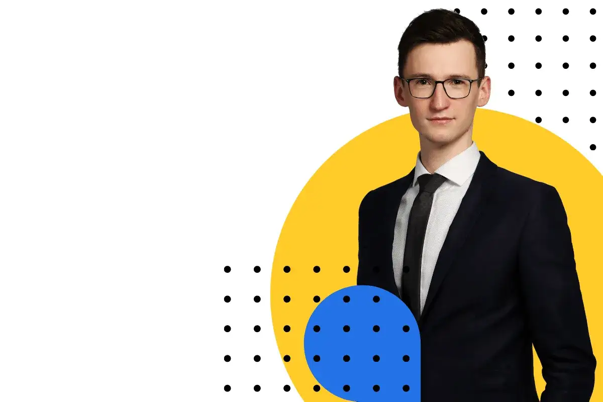 Mężczyzna w garniturze i okularach na tle geometrycznych kształtów.