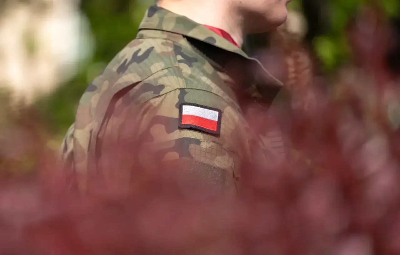 Żołnierz w mundurze moro z polską flagą na ramieniu, symbol służby i przyszłej emerytury wojskowej.