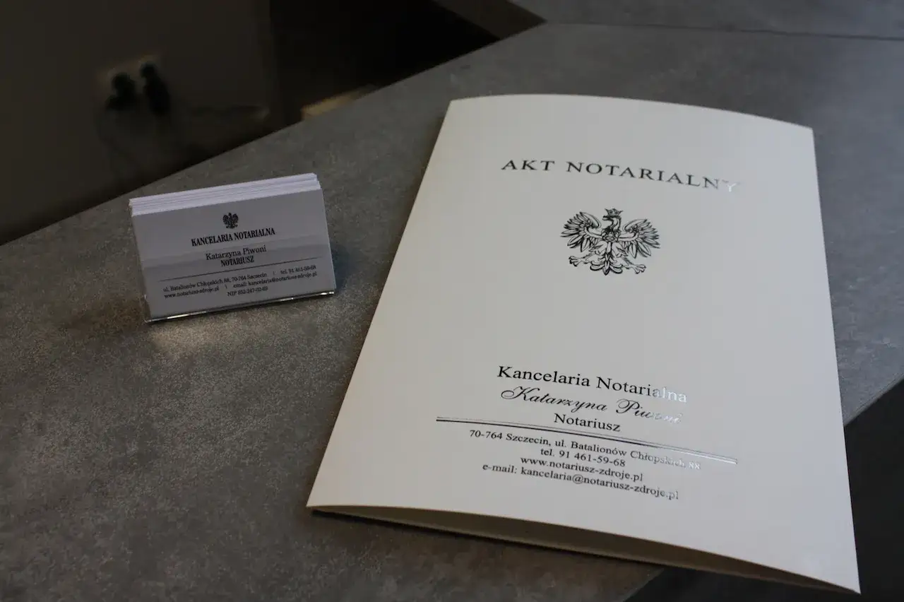 Akt notarialny i wizytówki Kancelarii Notarialnej Katarzyny Piwoni. Dokumenty te mogą być kluczowe przy sporządzaniu testamentu notarialnego.