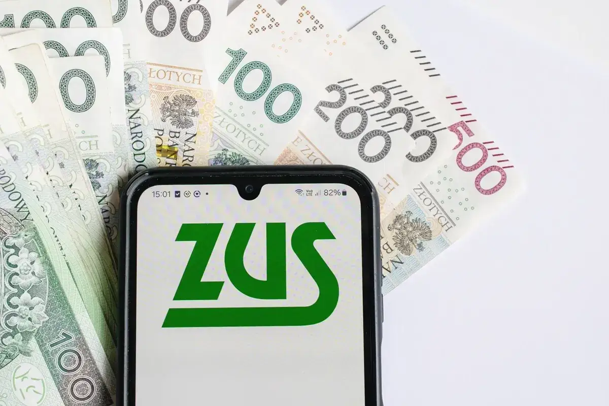 Telefon z logo ZUS na tle polskich banknotów. Wszyscy zastanawiają się, kiedy będą wypłacane czternastki.