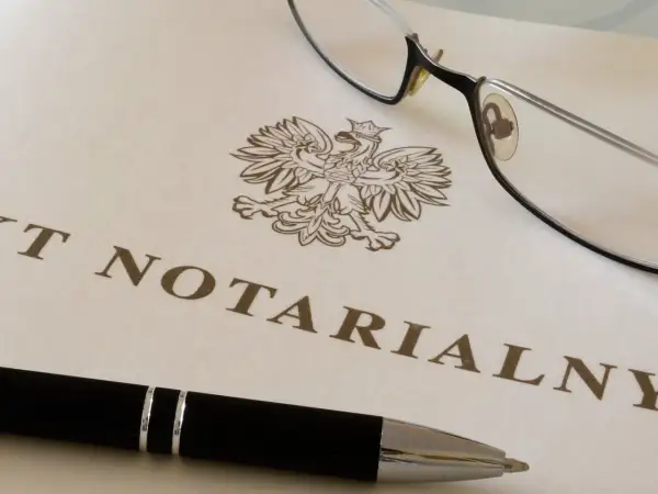 Okulary i długopis leżą na dokumencie z godłem Polski i napisem "AKT NOTARIALNY". To dokument, który wymaga opłaty, czyli taksa notarialna.
