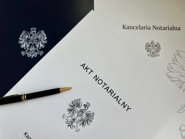 Elegancki długopis leży obok dokumentu z napisem "AKT NOTARIALNY" i godłem Polski.
