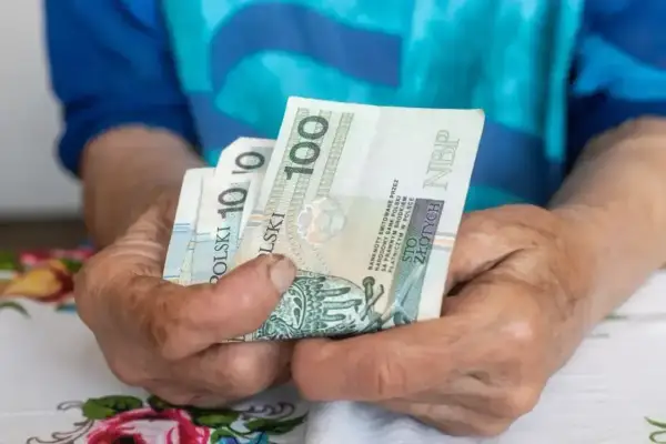 Dłonie trzymają polskie banknoty. Zastanawiasz się, ile wynosi umowa zlecenie na godzinę netto?
