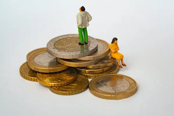Figurki ludzi na stosie monet. Jedna osoba stoi na szczycie, druga siedzi obok. Symbolizuje to opłatę skarbową i jej wpływ na finanse.