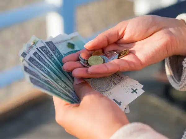 Dłonie liczą pieniądze, symbolizując oszczędności na przyszłość, być może związane z wiekiem emerytalnym kobiet.