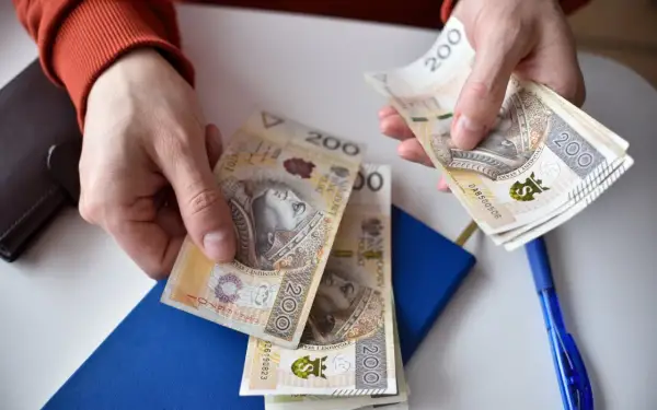 Ręce liczą banknoty 200 zł. Może to być wypłata, oszczędności, albo nawet renta alkoholowa, którą ktoś chce przeznaczyć na coś innego.