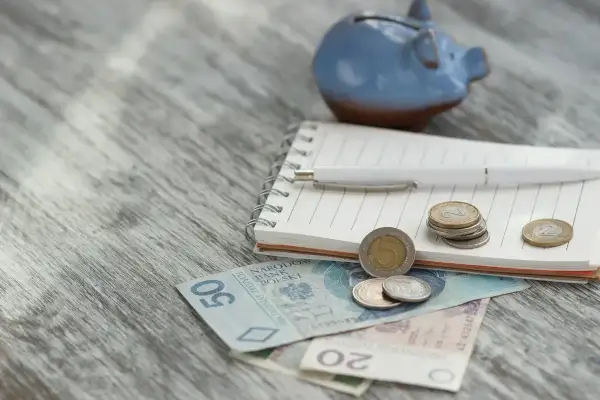 Niebieskana świnka-skarbonka, notatnik, długopis i polskie pieniądze. Planowanie wydatków, może na zasiłek okresowy?