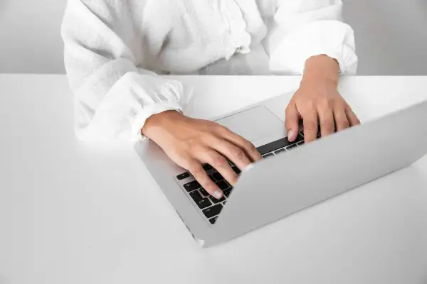 Dłonie piszą na laptopie, szukając informacji o zaświadczenie o niezaleganiu ZUS.