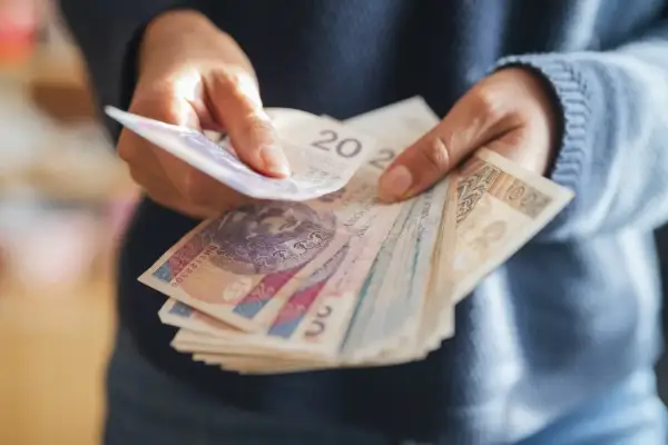 Ręce liczą polskie banknoty. Dyskusja na forum: emerytura z OFE po 65 roku życia.