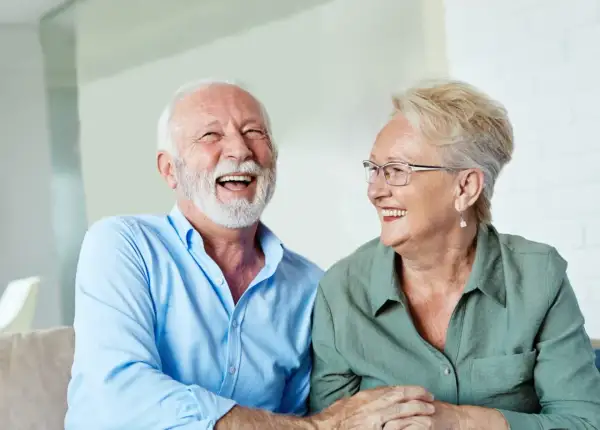 Szczęśliwi seniorzy śmieją się, omawiając zwrot podatku od 13 i 14 emerytury w tabeli.