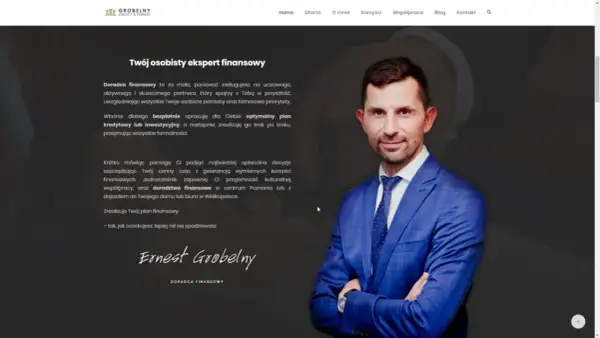 Mężczyzna w niebieskiej marynarce z krawatem, uśmiecha się, stojąc na tle strony internetowej.