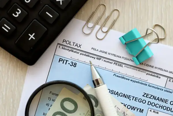 Rozliczenie dochodów z zagranicy przykład: PIT-38, kalkulator, lupa i pieniądze.