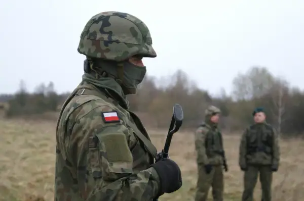 Żołnierz w kamuflażu, z polską flagą na ramieniu, trzyma broń. Zastanawiasz się, ile zarabia żołnierz netto?