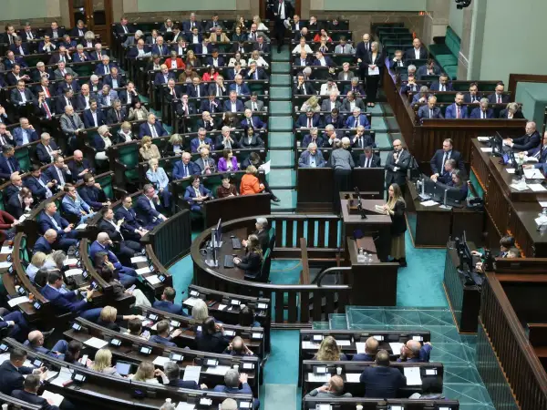 Posłowie w sali sejmowej, dyskutują o tym, ile wynosi dieta poselska.